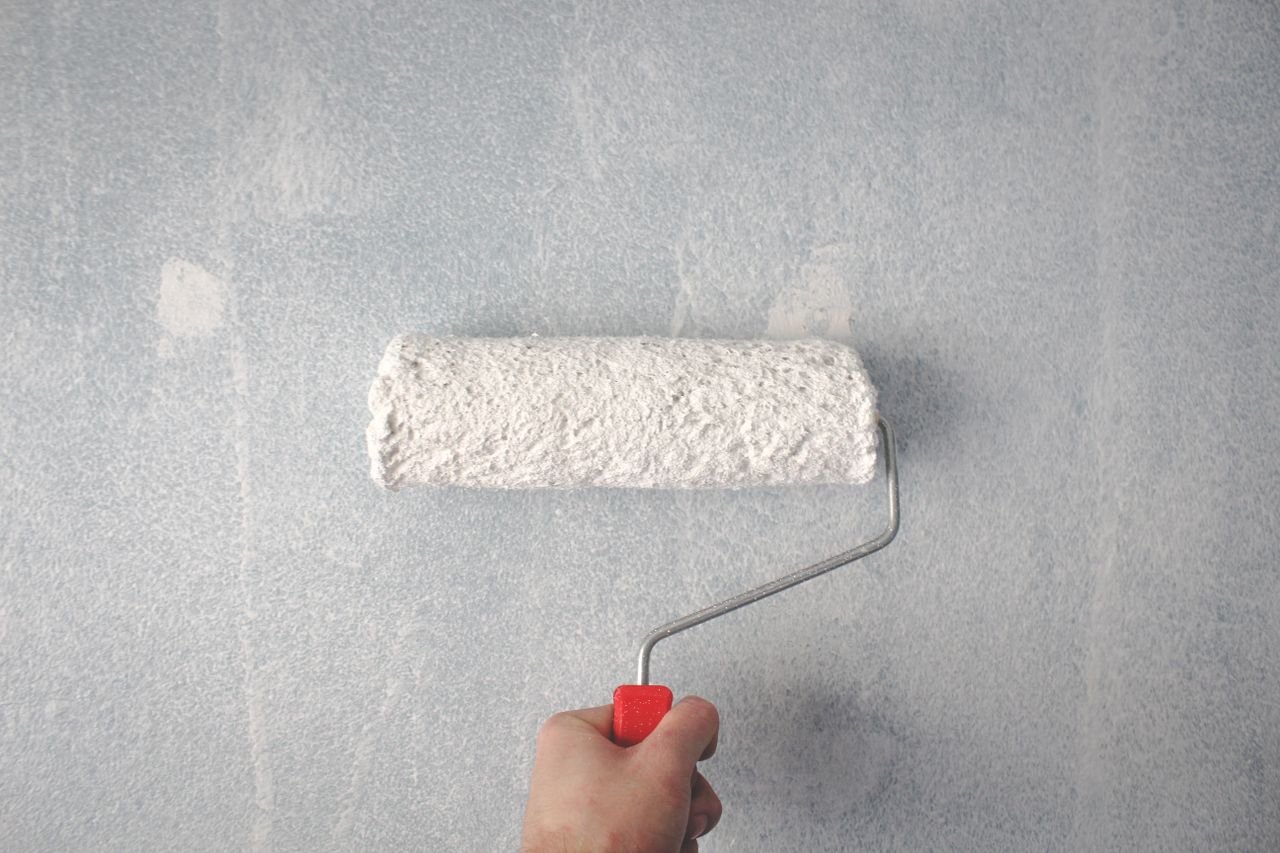 Hand mit einer Farbrolle beim Streichen einer Wand